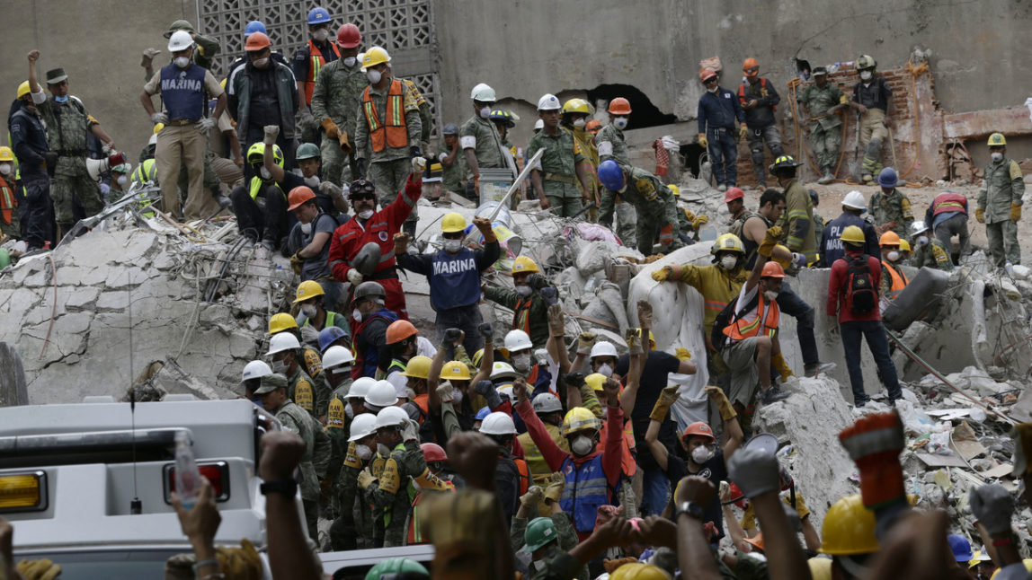 Search and rescue team members hold up closed fists motioning for silence during rescue efforts at a collapsed building in La Condesa neighborhood of Mexico City, Thursday, Sept. 21, 2017. Thousands of professionals and volunteers are working frantically at dozens of wrecked buildings across the capital and nearby states looking for survivors of the powerful quake that hit Tuesday. (AP/Marco Ugarte)