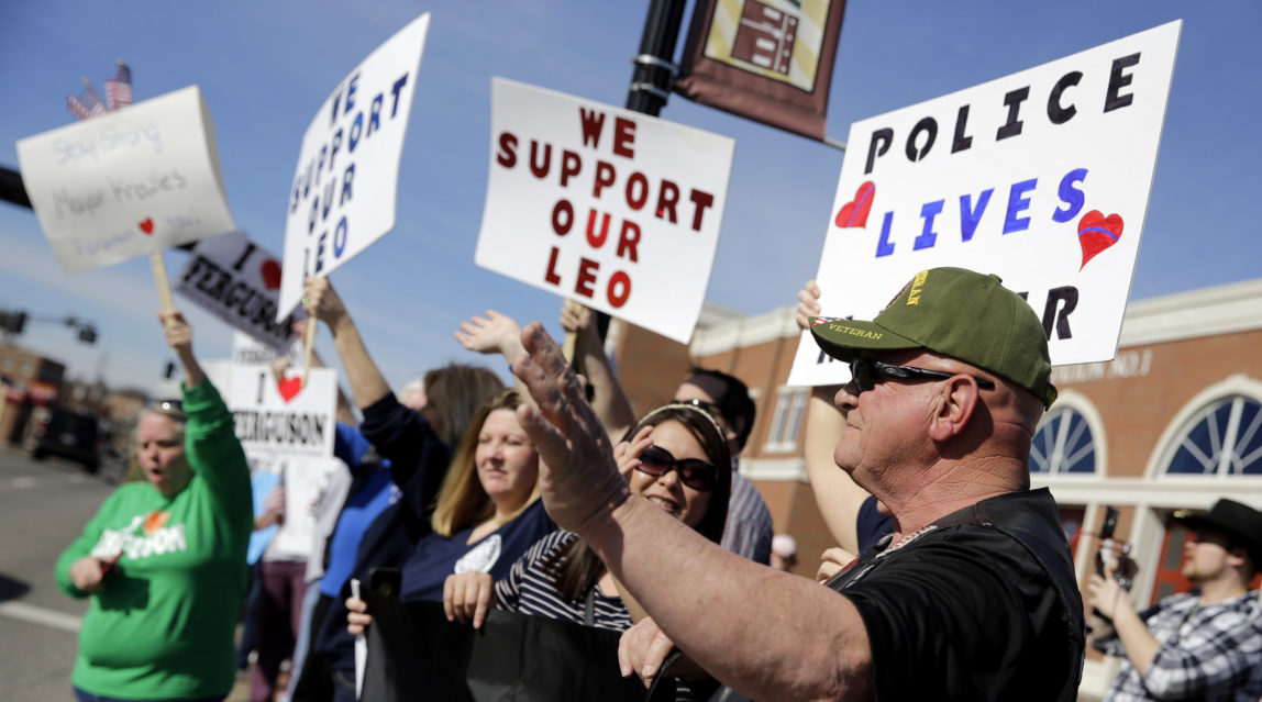 Pro-police demonstrators wave to passing cars as they stand outside the Ferguson Police Department Sunday, March 15, 2015, in Ferguson, Mo. (AP Photo/Jeff Roberson)
