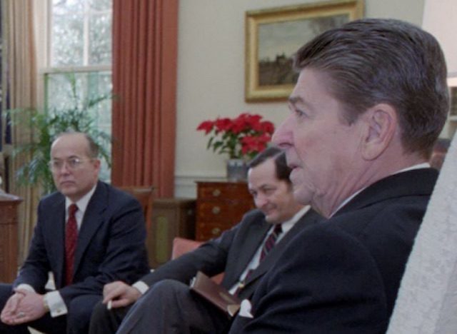 Partially obscured by President Reagan, Walter Raymond Jr. was the CIA propaganda and disinformation specialist who oversaw “political action” and “psychological operations” projects at the National Security Council in the 1980s. Raymond is seated next to National Security Adviser John Poindexter. (Photo credit: Reagan presidential library)