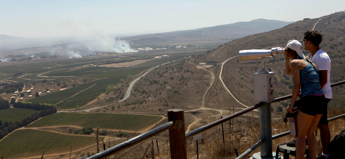 Israeli tourists watch smoke rising near the Syrian-Israeli border as the fighting Syrian army fights to regain control of the Quneitra border crossing from rebel groups. (Atef Safadi/EPA)
