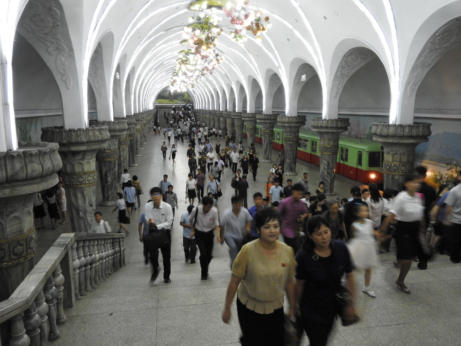 Pyongyang's metro is a three minute escalator ride below ground into a series of marble stations with elaborate chandeliers and beautiful wall paintings. Passengers ranged from well-dressed people, women in nice dresses and high heels, and others in casual blouses and slacks. Mosaics and engravings depict scenes of farming, construction, factories, rebuilding. Riding the metro costs the equivalent of a few cents. The tour group, Uri Tours, writes that half a million people ride the subway daily. 