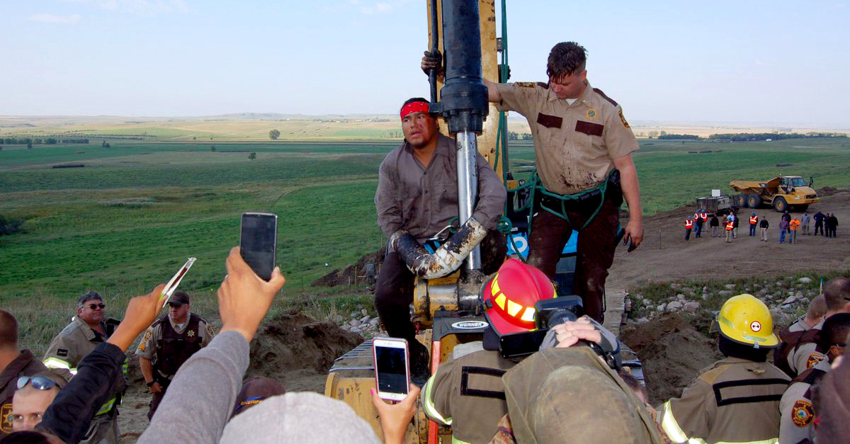 A pipeline protester uses PVC pipes to attach himself to a piece of construction equipment along Highway 6 near Bismarck, N.D. (Photo: Phil McKenna/Inside Climate News)