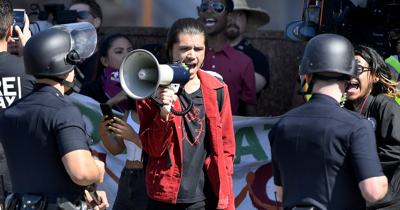 A protestor shouts at cops with a bullhorn on Wilshire Boulevard, outside the Federal Building in Westwood, Calif., as DACA supporters square off with LAPD on deadline day for DACA renewals Thursday, Oct. 5, 2017. ( John McCoy/Los Angeles Daily News via AP)