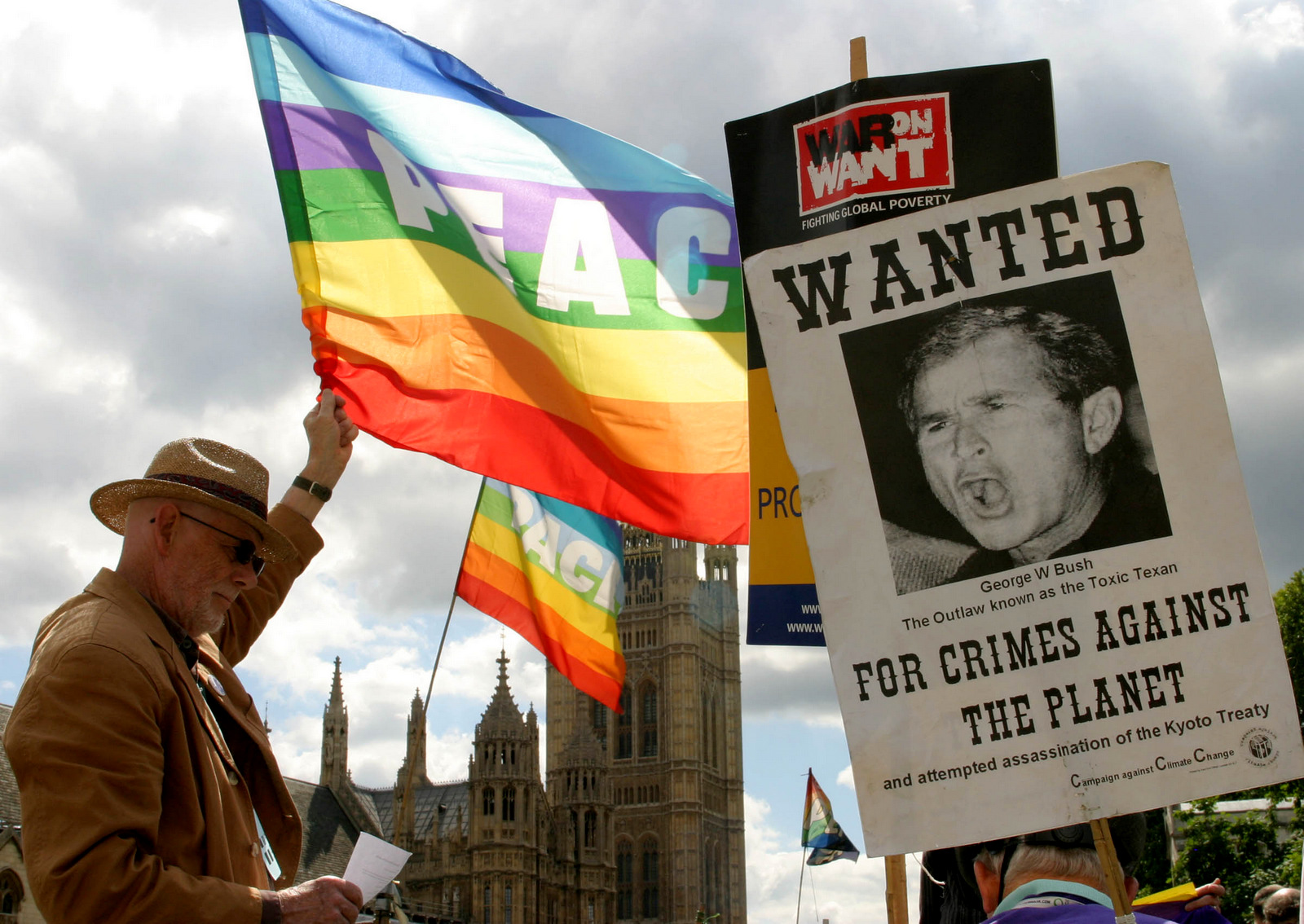 A protester holds up a peace flag next to a wanted poster of U.S. President George W. Bush during a demonstration at Westminster Square in London, Sunday, Aug. 7, 2005. (AP/Sergio Dionisio)