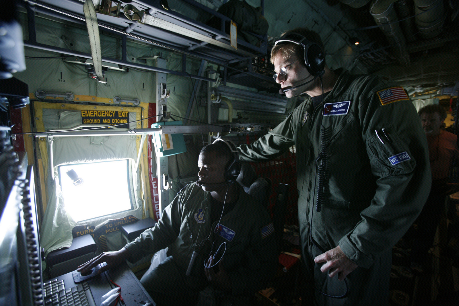 Tech. Sgt. Troy Bickham, left, and weather officer Maj. Brian Schroeder watch information coming in on a computer screen after having launched a dropsonde, a cardboard tube, about the length of a person's forearm and stuffed with sensors, from an Air Force Reserve C-130 Hurricane Hunter plane as the crew flys through the center of Tropical Storm Gustav, Wednesday, Aug. 27, 2008. (AP/Wilfredo Lee)