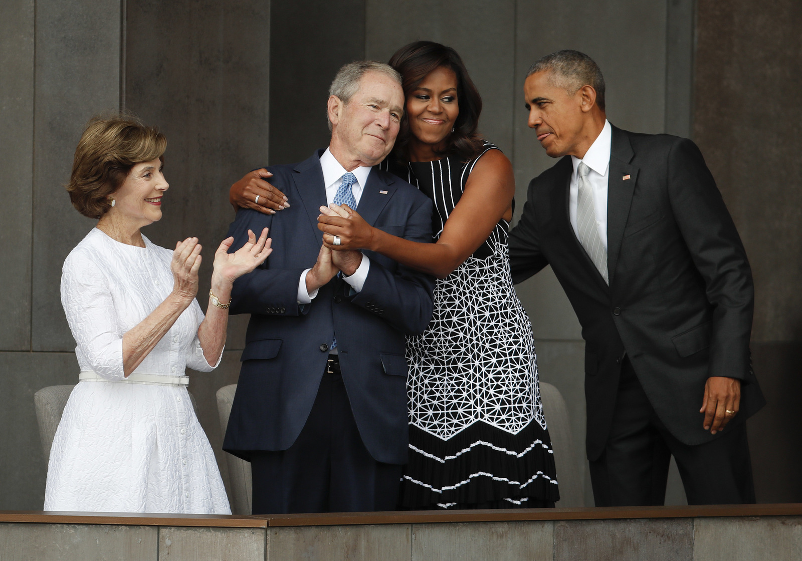 First lady Michelle Obama, center, hugs former President George W. Bush, as President Barack Obama and former first lady Laura Bush walk on stage at the dedication ceremony of the Smithsonian Museum of African American History and Culture on the National Mall in Washington, Saturday, Sept. 24, 2016. (AP/Pablo Martinez Monsivais)