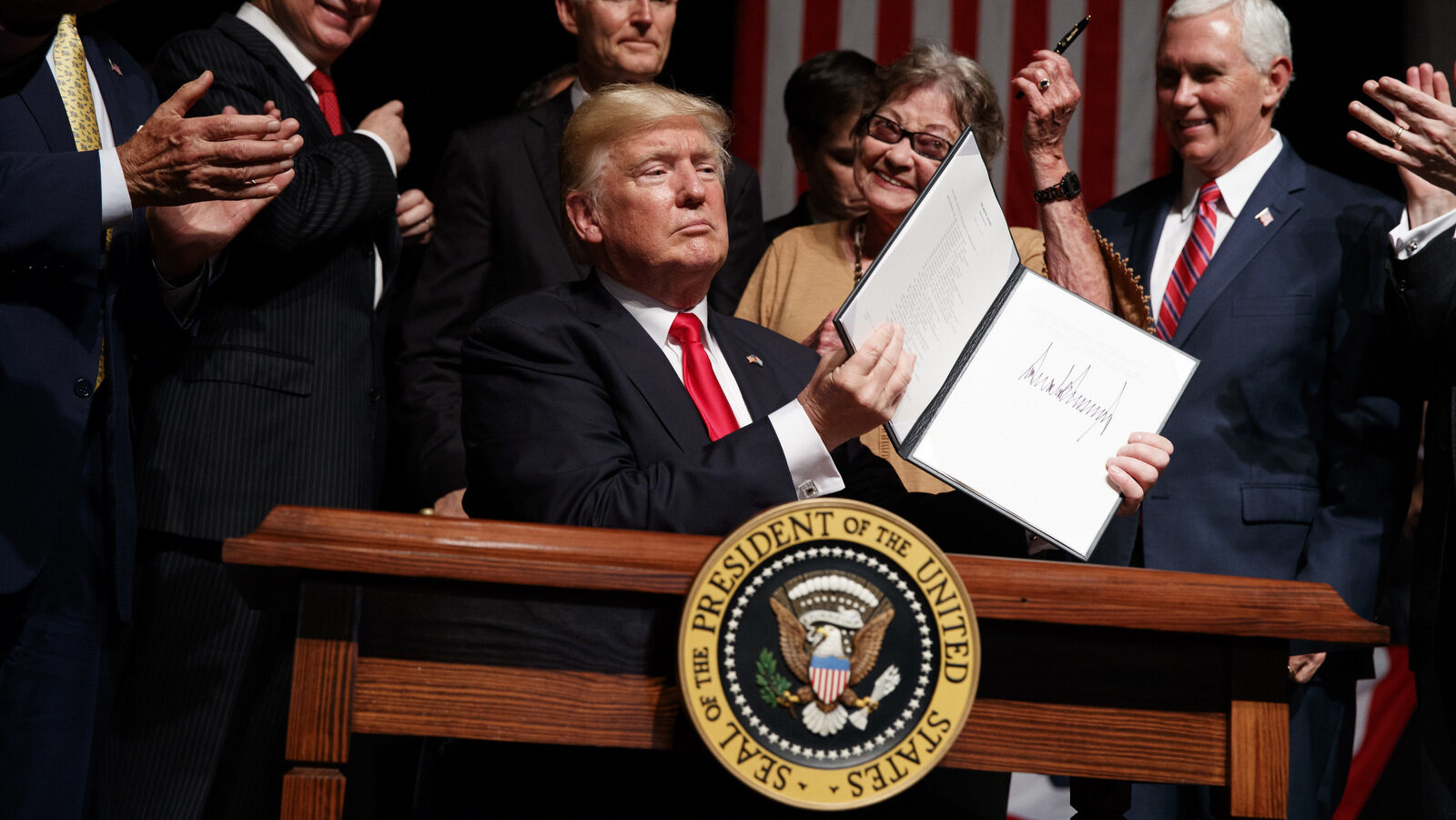 President Donald Trump shows a signed executive order on Cuba policy, Friday, June 16, 2017, in Miami. From left are, Rep, Mario Diaz-Balart, R-Fla., Florida Gov. Rock Scott, Cary Roque, and Vice President Mike Pence. (AP Photo/Evan Vucci)