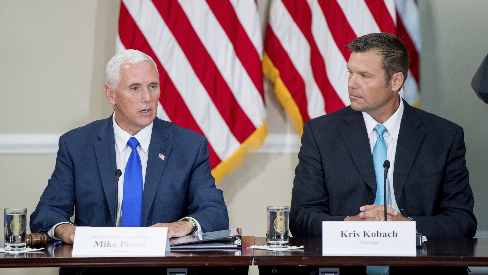 Vice President Mike Pence, left, accompanied by Vice-Char Kansas Secretary of State Kris Kobach, right, speaks during the first meeting of the Presidential Advisory Commission on Election Integrity at the Eisenhower Executive Office Building on the White House complex in Washington, Wednesday, July 19, 2017. (AP Photo/Andrew Harnik)
