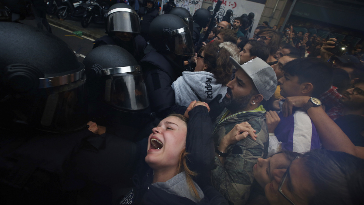 In this Sunday, Oct. 1, 2017 photo a girls grimaces as Spanish National Police pushes away Pro-referendum supporters outside the Ramon Llull school assigned to be a polling station by the Catalan government in Barcelona, Spain. (AP/Emilio Morenatti)