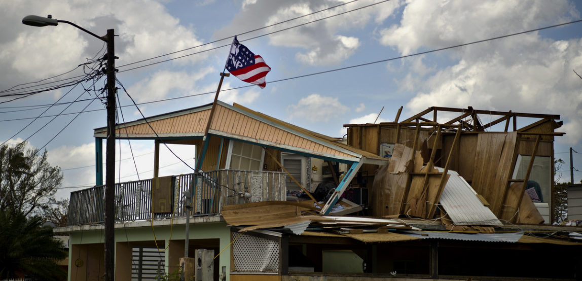 A political party banner waves over a home damaged in the passing of Hurricane Maria, in the community of Ingenio in Toa Baja, Puerto Rico, Monday, Oct. 2, 2017. (AP Photo/Ramon Espinosa)