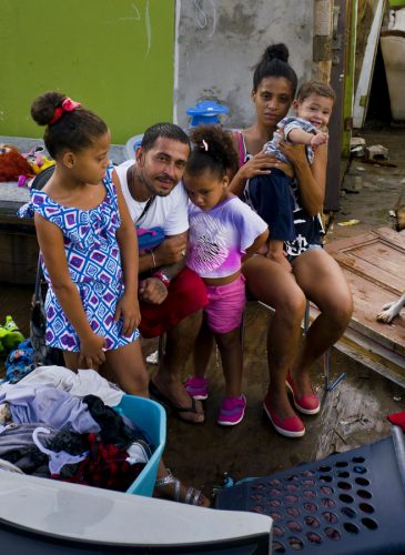 In this Saturday, Oct. 14, 2017 photo, Arden Dragoni, second from left, poses with his wife Sindy, their three children and dog Max, surrounded by what remains of their home destroyed by Hurricane Maria in Toa Baja, Puerto Rico. The Dragoni family has been living in a shelter set up at a school since the storm destroyed their wooden home in late September. They lost everything: clothes, household goods, and an old car. Dragoni supported his family by working construction, but his employers are currently out of business, leaving him and his family without a source of income. (AP/Ramon Espinosa)