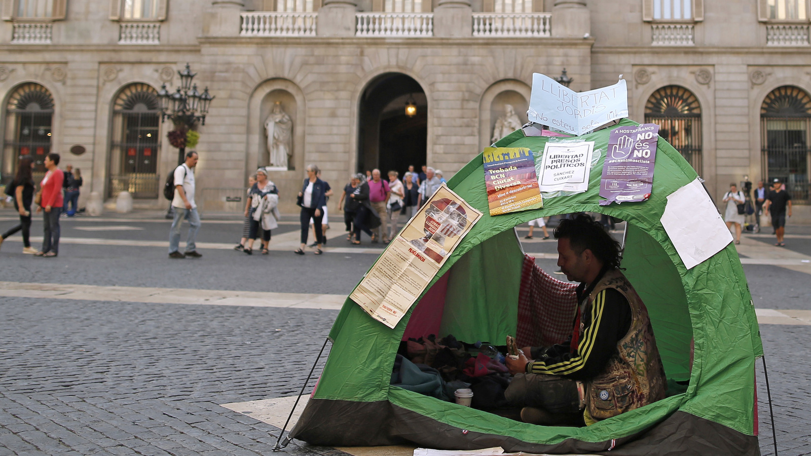 A man eats a sandwich as he camps protesting for the National Court decision to imprison civil society leaders without bail in front of the Palau Generalitat in Barcelona, Spain, Tuesday, Oct. 17, 2017. A Spanish judge's decision to jail the leaders of two Catalan grassroots groups, Catalan National Assembly and Omnium Cultural, was met with a chorus banging pots and pans, honking car horns and clapping in the streets of Barcelona. (AP Photo/Manu Fernandez)