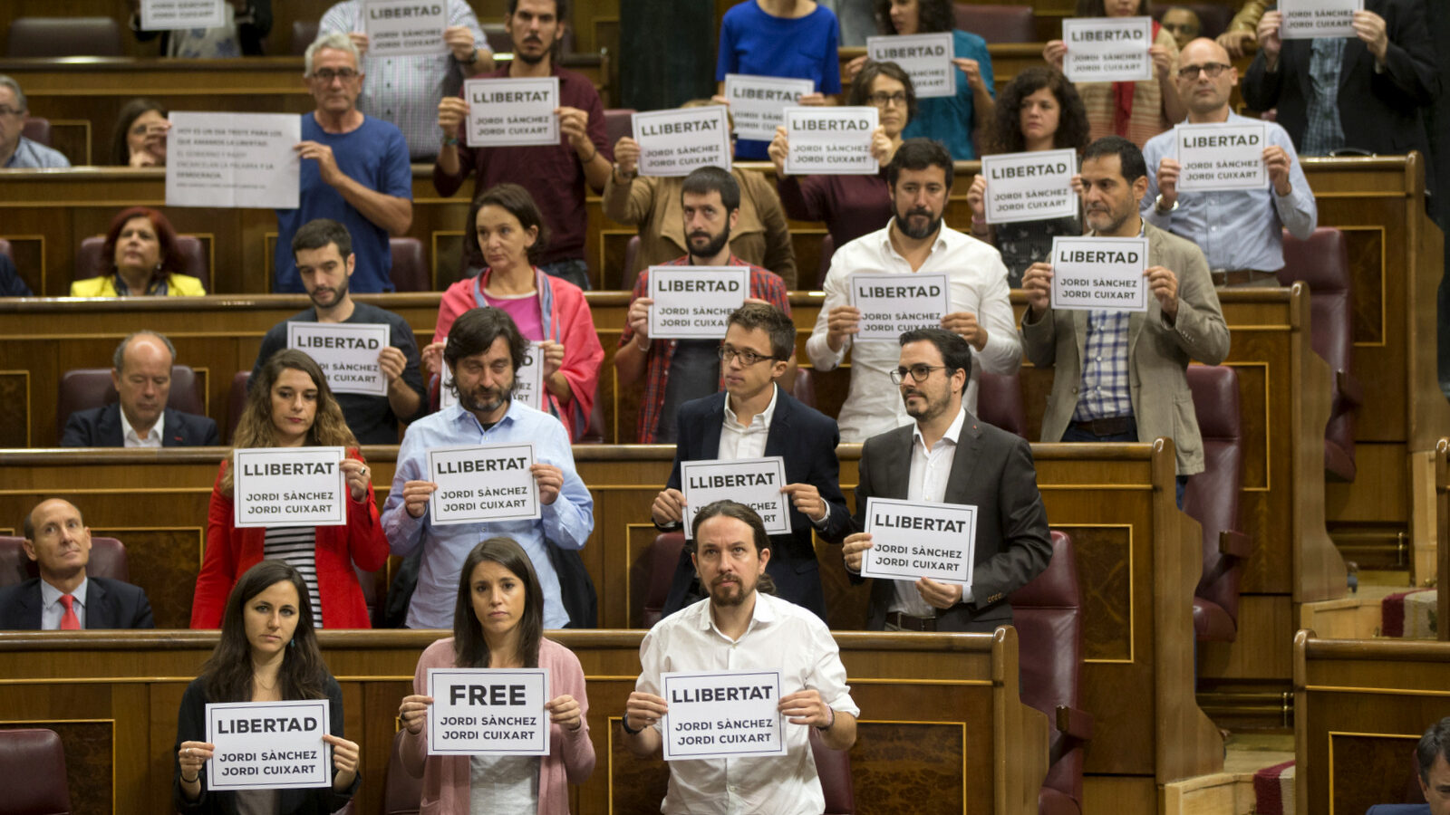 Lawmakers hold up posters reading: "Free Jordi Sanchez and Jordi Cuixart," leaders of the Catalan grassroots organizations Catalan National Assembly and Omnium Cultural, during a parliamentary session at the Spanish parliament in Madrid, Wednesday, Oct. 18, 2017. About 50 Spanish and Catalan party lawmakers held up posters in the parliament demanding the release of two pro-Catalonia independence movement leaders, describing them as political prisoners. (AP/Francisco Seco)