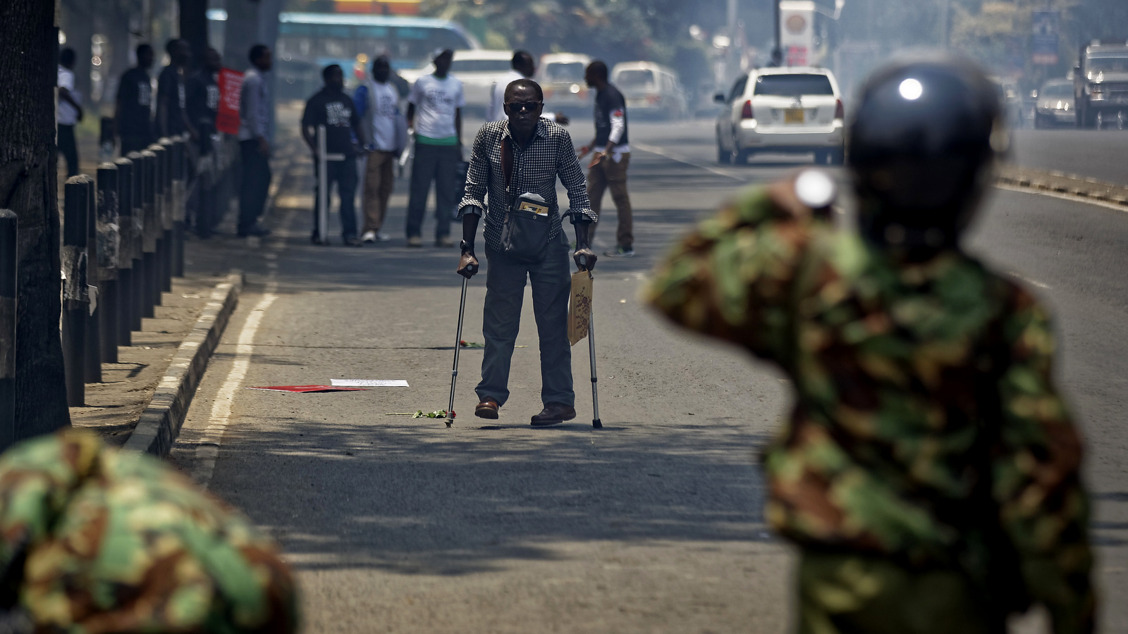 A pedestrian walking with crutches tries to flee as police fire tear gas grenades, at demonstration against police killings of protesters and opposition supporters, in downtown Nairobi, Kenya, Oct. 19, 2017. Police fired tear gas grenades and rifles in the air to disperse around 20 activists as they were still gathering in Uhuru Park, despite a court order Tuesday that removed the government's ban on demonstrations. (AP/Ben Curtis)