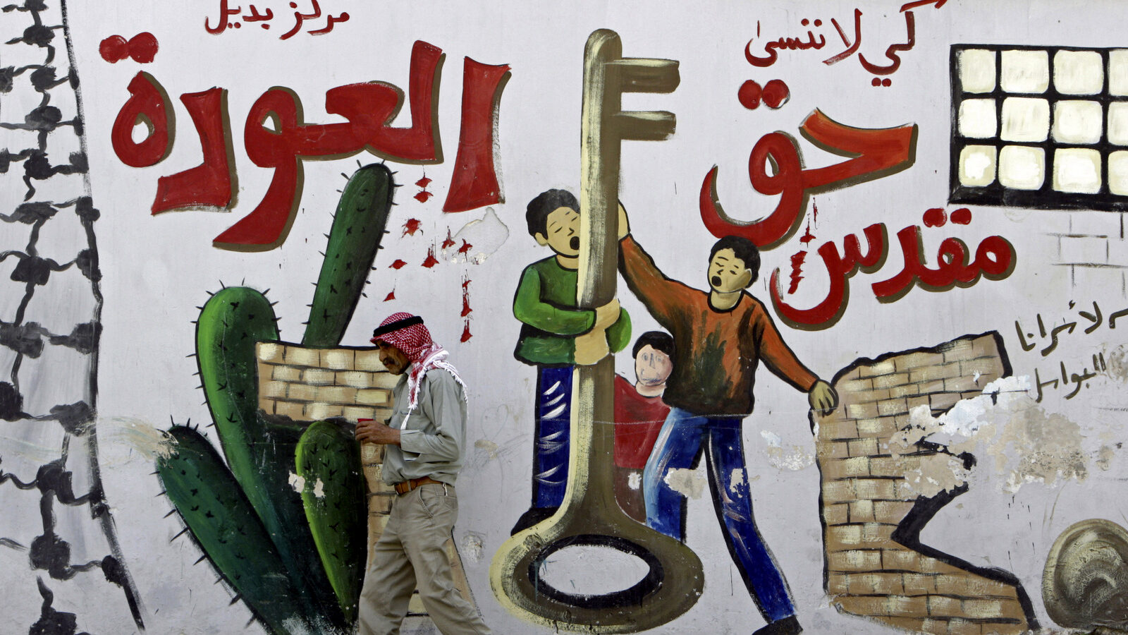 Palestinian refugee Mahmoud Al-Amer, 78, walks past a mural in the West Bank refugee camp of Jenin , Monday, May 13, 2013. Arabic on the mural reads, '"we must never forget, the return is a sacred right." (AP/Mohammed Ballas)