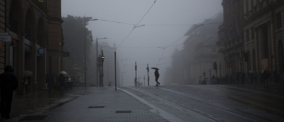 A woman takes shelter under an umbrella from light drizzle on a foggy day as she walks across a street in Edinburgh, Scotland, Monday, Sept. 15, 2014. (AP/Matt Dunham)