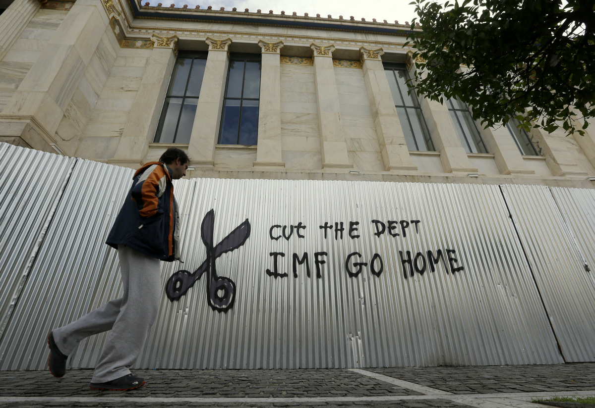 A pedestrian passes anti-austerity graffiti in front of Athens Academy. (AP/Thanassis Stavrakis)
