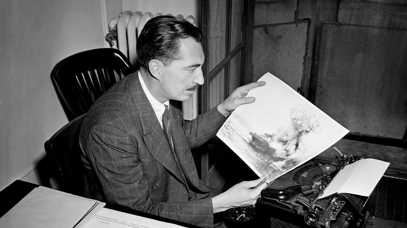 Stanley Johnston, Chicago Tribune correspondent is pictured in Chicago, June 12, 1942. The only American newsman aboard the U.S. aircraft carrier Lexington, Johnston looks at an Associated Press WirePhoto transmission of a Navy picture showing the Lexington as it exploded during the battle of Coral Sea. (AP/Paul Cannon)