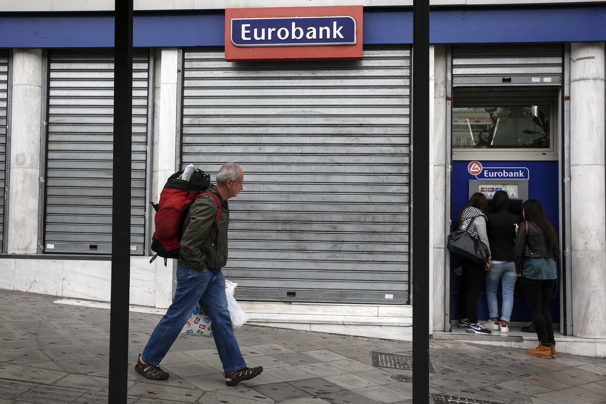 A tourist makes his way as youths make a transaction at an automated teller machine (ATM) of a Eurobank Bank branch in Athens, Saturday, Oct. 31, 2015. The European Central Bank says Greece's battered banks need 14.4 billion euros ($15.8 billion) in fresh money to get back on their feet and resume normal business. (AP Photo/Yorgos Karahalis)