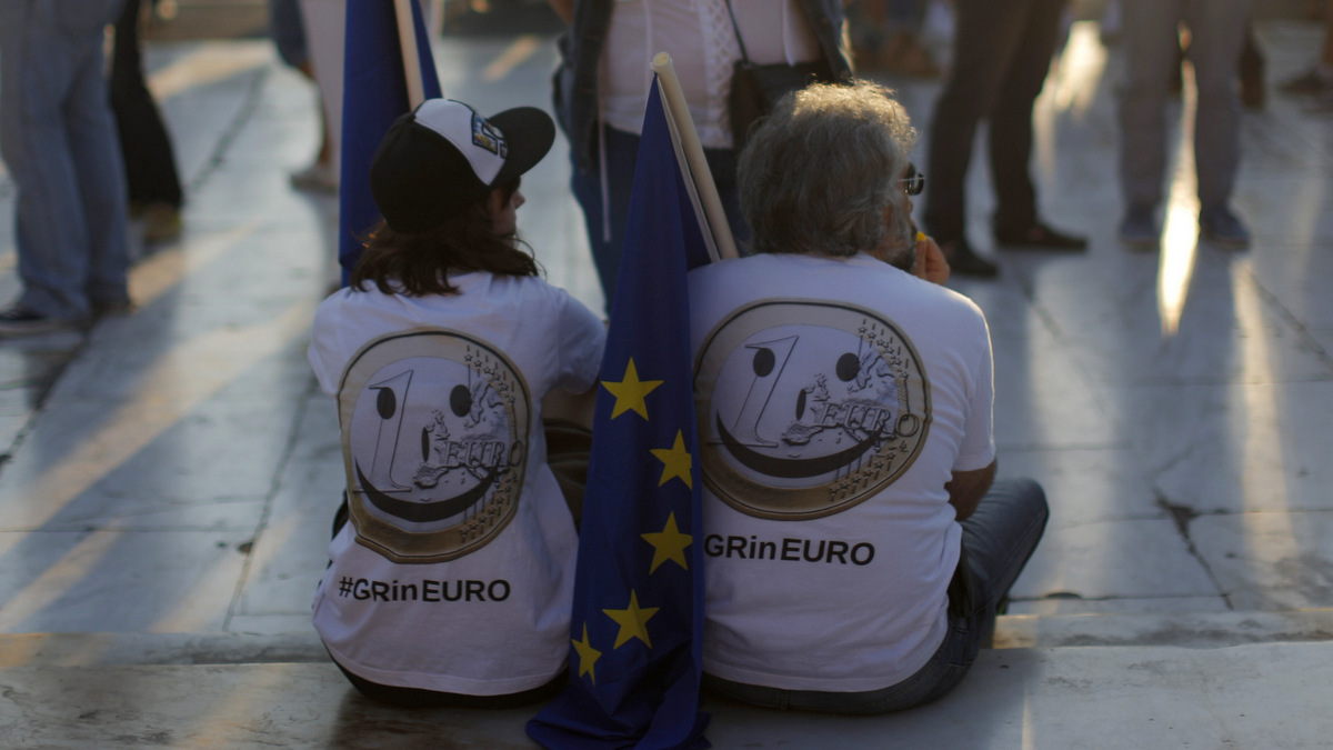 Pro-Euro demonstrators, wearing t-shirts depicting the one Euro coin, sit on a sidewalk during a rally at Syntagma square in Athens, Thursday, July 9, 2015. (AP/Emilio Morenatti)
