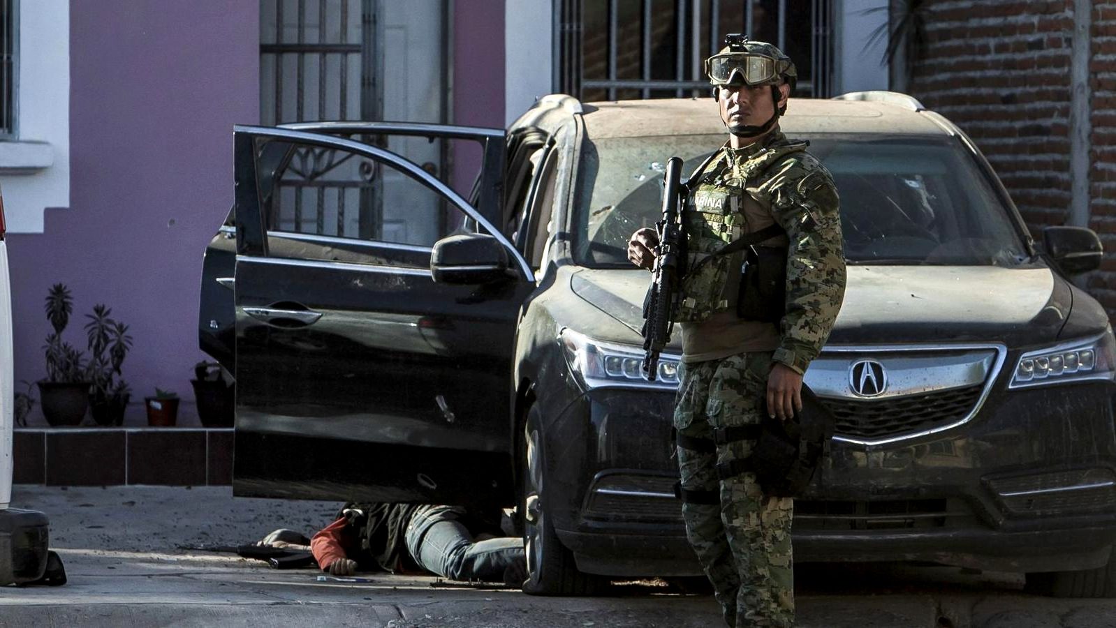 A Mexican marine stands by the body of a gunman after shots were exchanged in the city of Culiacan on Feb. 7, 2017. The Sinaloa state prosecutor's office said the men attacked the marines, leaving one of them dead. (Rashide Frias/Associated Press)