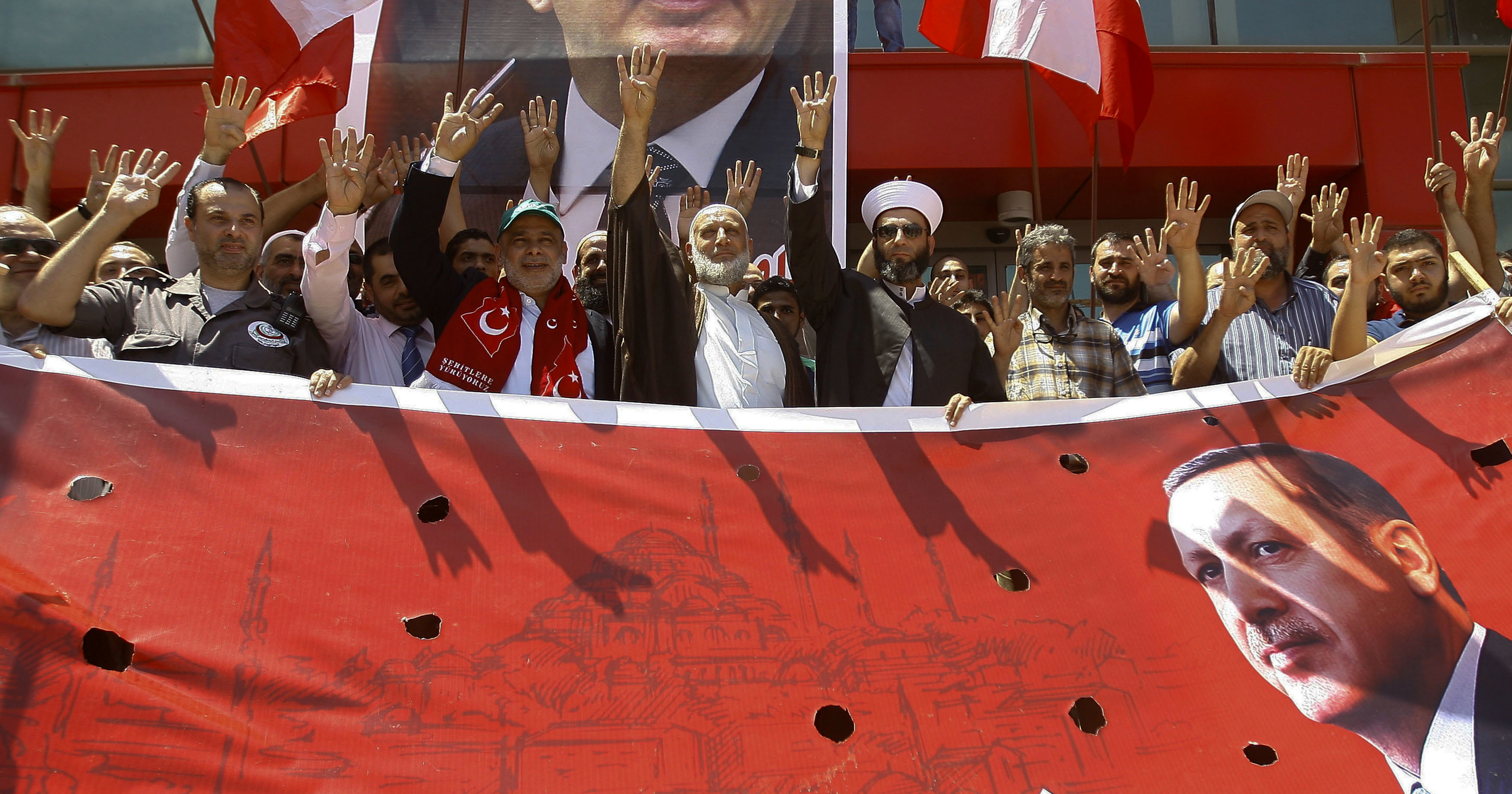 Supporters of Turkey's President Recep Tayyip Erdogan, making a four-fingered gesture referring to the 2013 killing of Muslim Brotherhood protesters at the Rabaah Al-Adawiya Mosque in Egypt, protest against the failed coup in Turkey, in front the Turkish hospital in the southern port city of Sidon, Lebanon, July 16, 2016. (AP/Mohammed Zaatari)