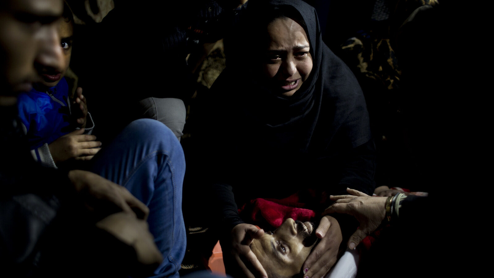 Relatives of Palestinian Muhammed al-Aqraa, who was killed in an explosion in a smuggling tunnel at the border between Gaza and Egypt, mourn over his body in his family house during his funeral, Thursday, Feb. 9, 2017. Palestinian officials say an Israeli pre-dawn airstrike has killed several Gaza residents and wounded five others in a smuggling tunnel along the border with Egypt. The bombing appears to be the first to target smuggling tunnels since the 2014 war between Israel and Gaza's Hamas rulers. (AP Photo/ Khalil Hamra)
