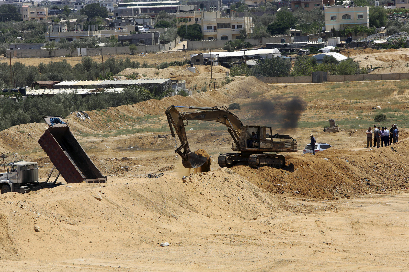A backhoe removes sand barriers to create a buffer zone along the Egyptian border with the Gaza strip, near entrances to smuggling tunnels, background, in Rafah, June 28, 2017. (AP/Adel Hana)