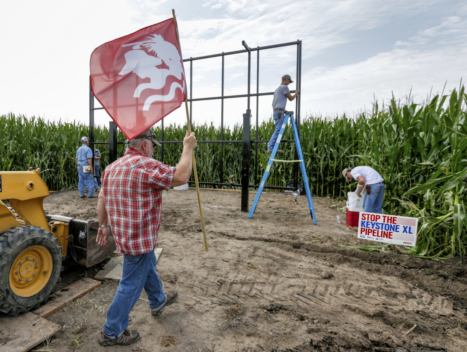 Tom Genung of the organization Bold Nebraska is about to pitch a flag of the Cowboy Indian Alliance at the proposed path of the Keystone XL pipeline, in Silver Creek, Neb., where landowner Jim Carlson and activists were building solar panels, July 29, 2017 (AP/Nati Harnik)