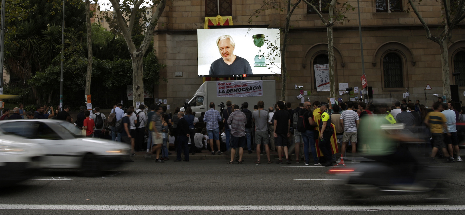 People watch a video conference of WikiLeaks founder Julian Assange outside the public university in Barcelona, Spain, Tuesday, Sept. 26, 2017. (AP/Manu Fernandez)