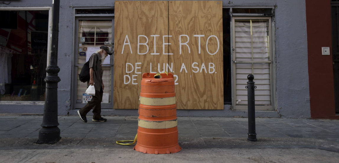 A man walks past a boarded up clock repair store in the tourist area of Old San Juan one month after Hurricane Maria in San Juan, Puerto Rico. (AP/Carlos Giusti)