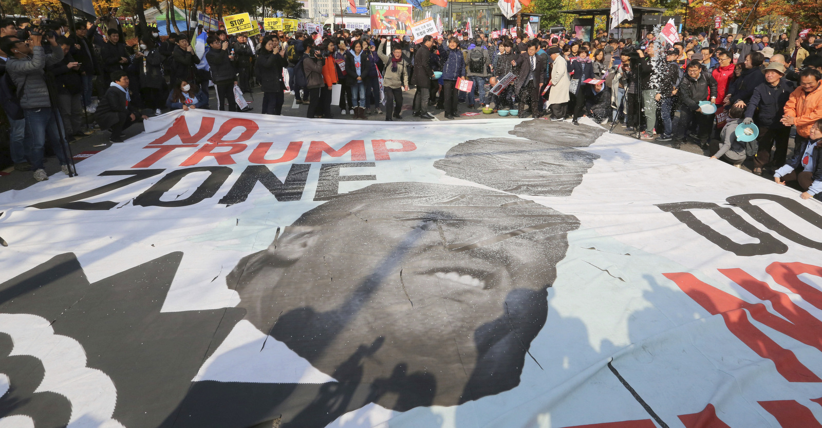 Members of "No Trump Coalition" hurl salt at a banner showing images of the U.S. President Donald Trump during a rally against his visit in front of the National Assembly in Seoul, South Korea, Nov. 8, 2017. (AP/Ahn Young-joon)