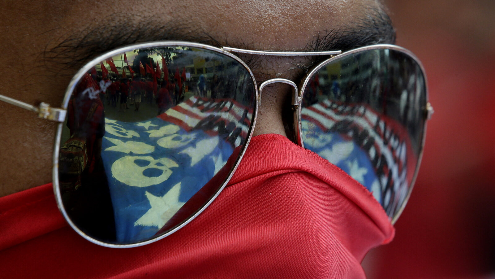 A mock U.S. flag is reflected on the eyeglasses of a protester during a rally near the venue of ASEAN summit and meetings in Manila, Philippines on Nov. 12, 2017. The group is protesting against the visit of U.S. President Donald Trump, who is currently on a trip to Asia with the Philippines as his last stop for the ASEAN leaders' summit and related summits between the regional grouping and its Dialogue Partners. (AP/Aaron Favila)