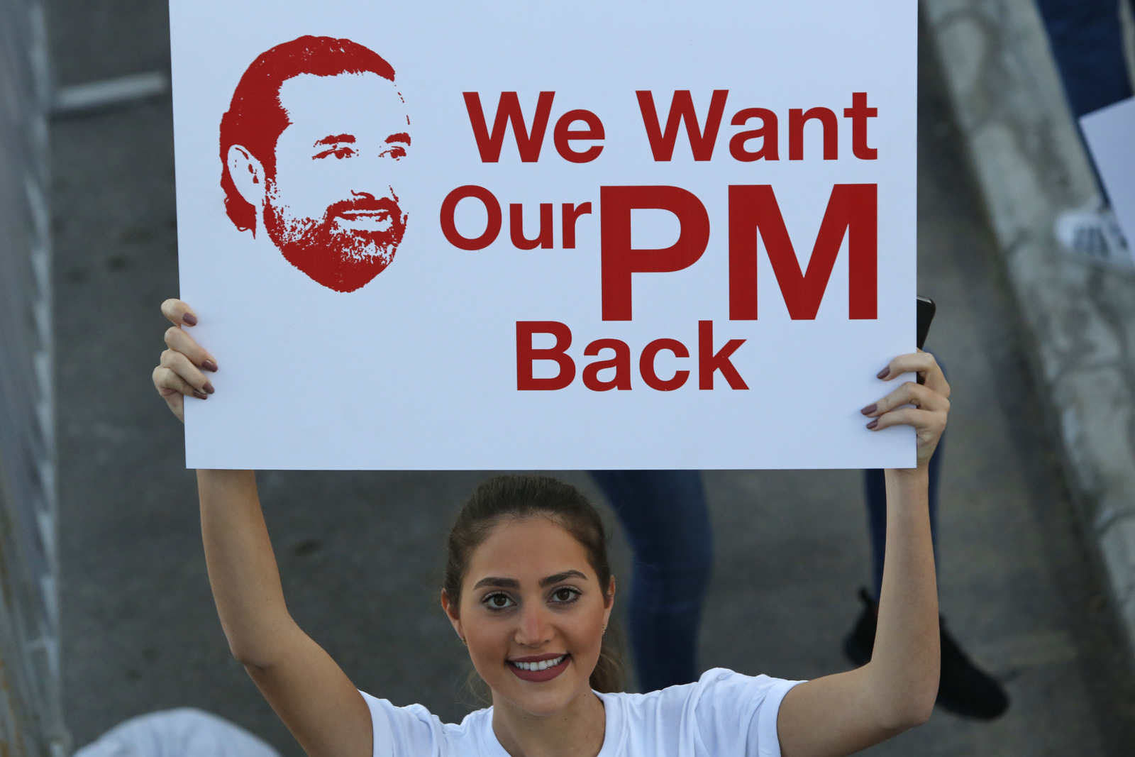 A Lebanese woman holds a placard supporting the outgoing Lebanese Prime Minister Saad Hariri to return from Saudi Arabia during the Beirut Marathon, in Beirut, Lebanon, Nov. 12, 2017. (AP/Hassan Ammar)