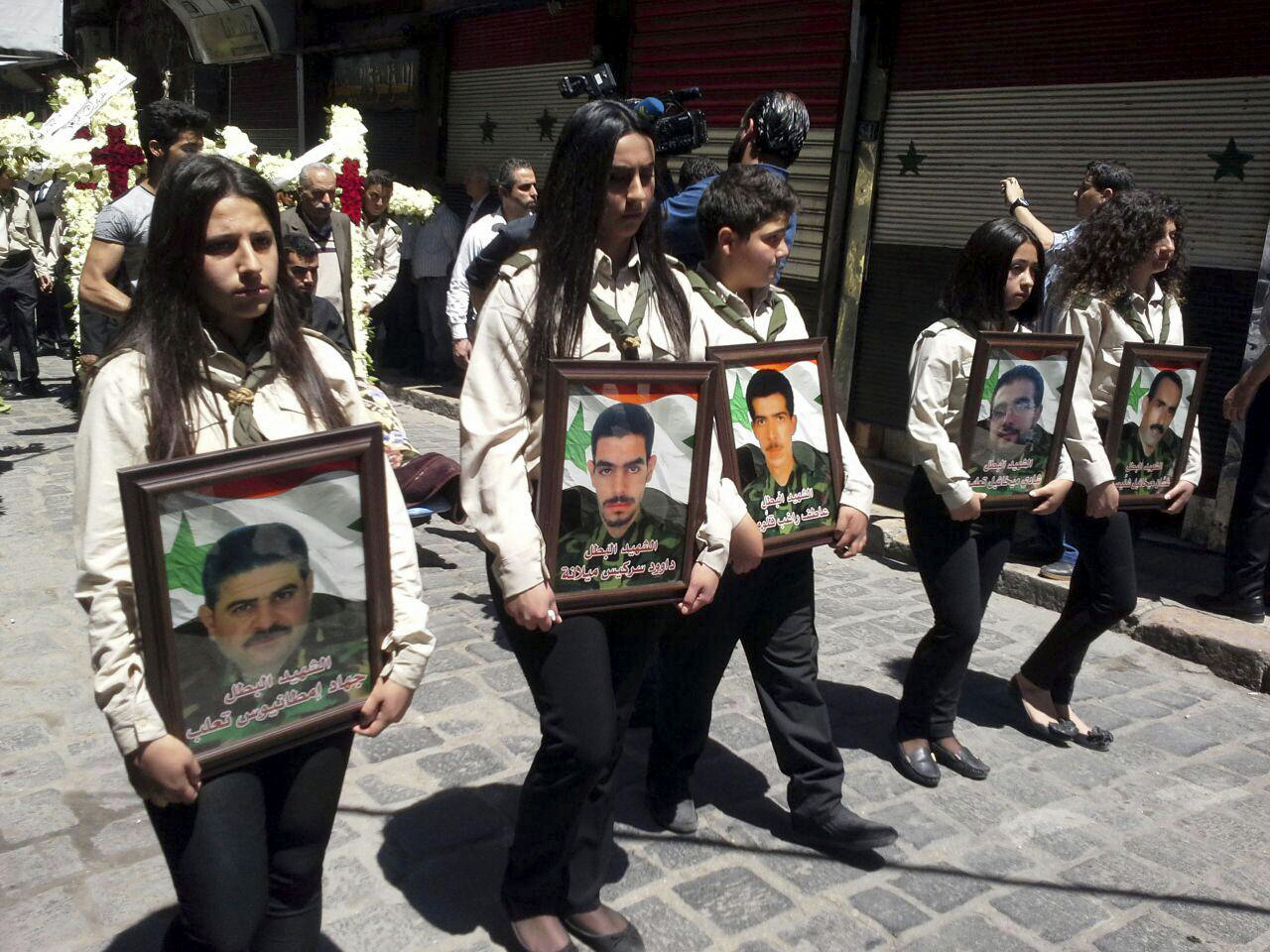 Girls carry the pictures of five Syrian Christian men who were kidnapped four years ago by rebel groups during their funeral prayers in Bab Touma, a predominantly Christian quarter of the Syrian capital Damascus, Syria, April 25, 2017. (SANA via AP)