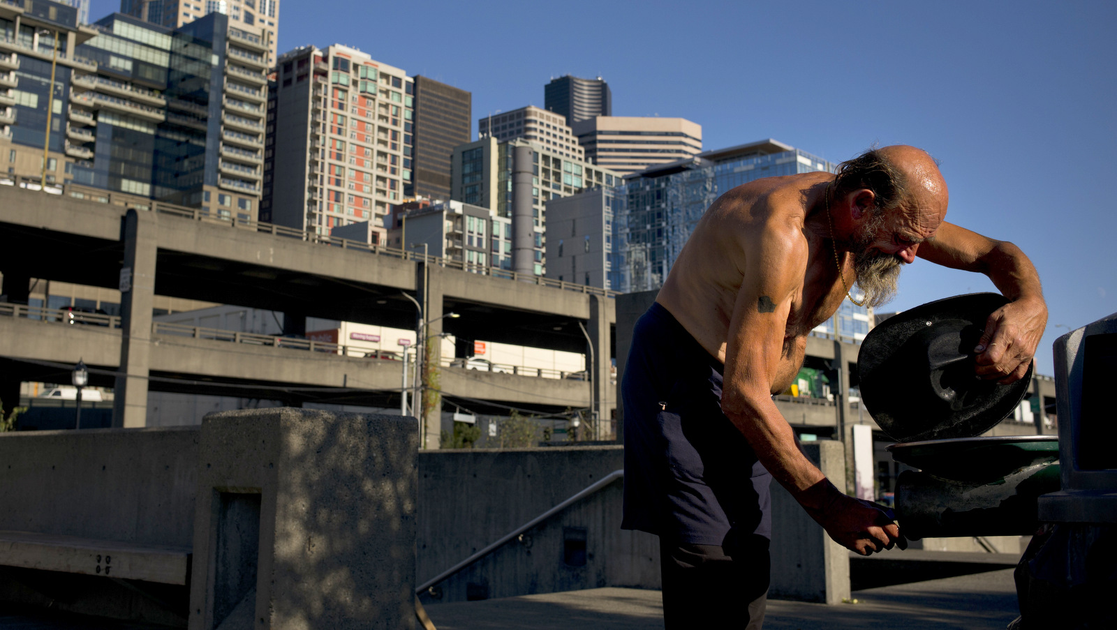 Joseph Nalty, a 64-year-old homeless man dampens his hat to cool off in the Waterfront Park area of Seattle, Sept. 28, 2017. A homeless crisis of unprecedented proportions is rocking the West Coast, and its victims are being left behind by the very things that mark the region's success: soaring housing costs, rock-bottom vacancy rates and a roaring economy. (AP/Jae C. Hong)