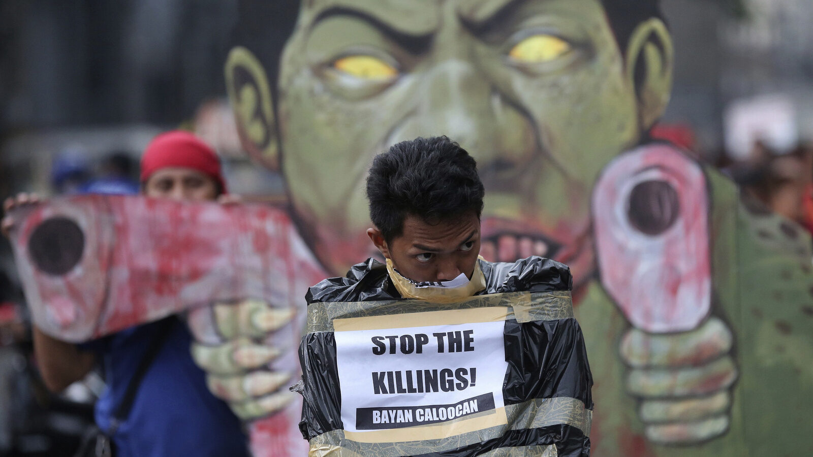 A protester is wrapped on a plastic bag to reenact alleged killings by police during a rally in Manila, Philippines, Dec. 8, 2017. Protesters were calling for the ouster of Duterte and denounced his dictatorial rule. (AP/Aaron Favila)