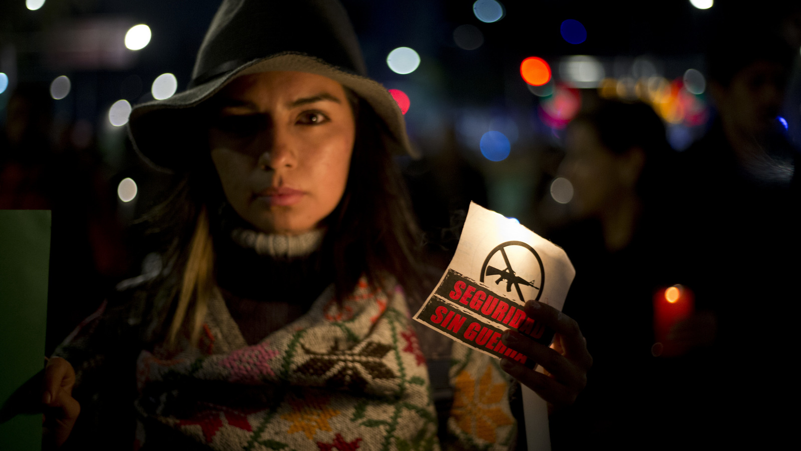 A woman carries a sign that says in Spanish "Security without war" during a candlelight protest against a newly proposed security law in Mexico City, Dec. 13, 2017. Mexico's ruling party rammed a bill through Congress' lower house on Dec. 7 giving the military legal justification to act as police, triggering objections by those who said it would effectively militarize the country. The legislation is now with the Senate. (AP/Eduardo Verdugo)