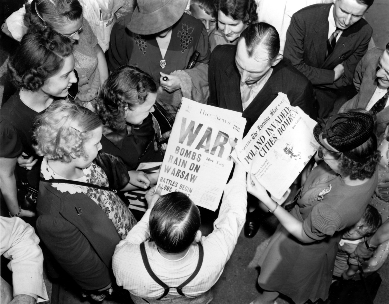 A crowd reads newspaper headlines "Bombs Rain On Warsaw" as they stand outside the U.S. State Department building where diplomats hold a conference on war conditions in Europe in Washington, D.C., Sept. 1, 1939. (AP Photo)