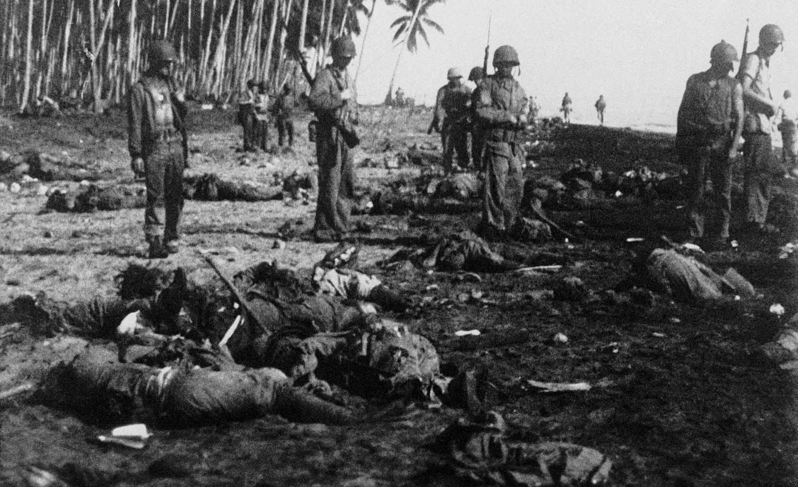 On the shore of Guadalcanal Island, U.S. Marines count Japanese dead after the Marines drove onto the island to take the strategic airport area, Oct. 27, 1942 in Solomon Island. (AP Photo)