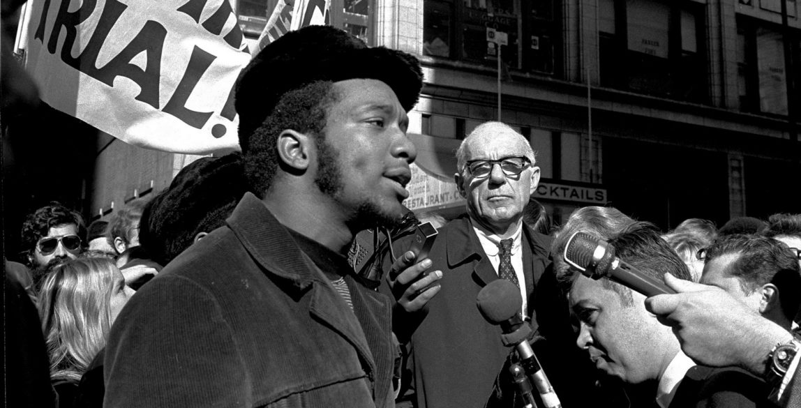 At a rally outside the U.S. Courthouse October 29, 1969, Dr. Benjamin Spock, background, listens to Fred Hampton, chairman of the Illinois Black Panther party speak at a protest against the trial of eight persons accused of conspiracy to cause a riot during the Democratic National Convention in 1968. (AP/stf)