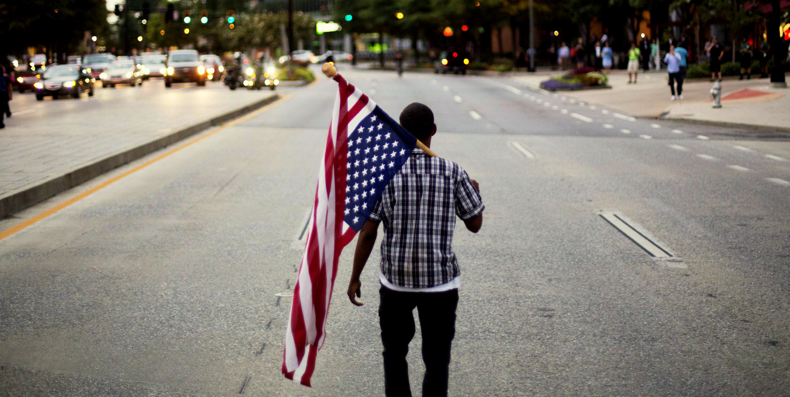 Skylar Barrett walks alone with an American flag in the middle of the street during a march through the Buckhead neighborhood against the recent police shootings of African-Americans on July 11, 2016, in Atlanta. (AP/David Goldman)