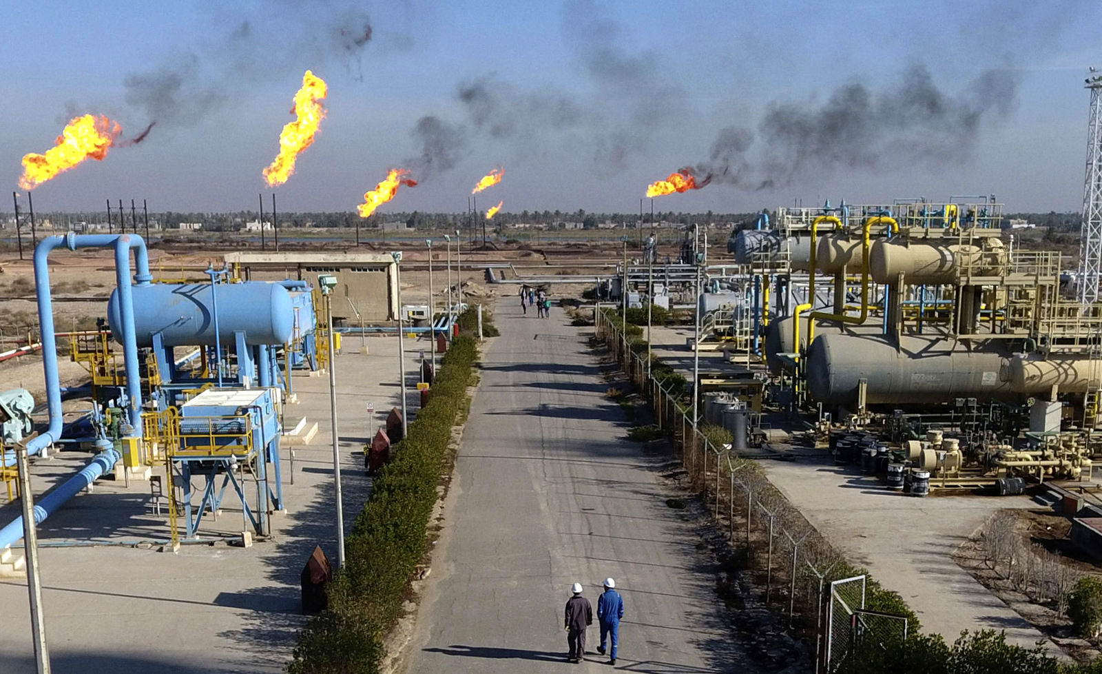 Laborers walk down a path in the Nihran Bin Omar field north of Basra, Iraq, 340 miles (550 kilometers) southeast of Baghdad, on Jan. 12, 2017. (AP/Nabil al-Jurani)