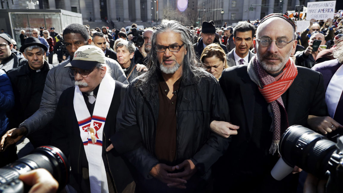 Ravi Ragbir, center, executive director of the New Sanctuary Coalition, walks with hundreds of supporters as he arrives for his annual check-in with Immigration and Customs Enforcement, March 9, 2017, in New York. The Trinidadian immigrant works with an interfaith network of congregations and activists working to protect New York's immigrant families from detention and deportation. He was convicted of wire fraud in 2001 and served his sentence but has now been deported. (AP/Mark Lennihan)