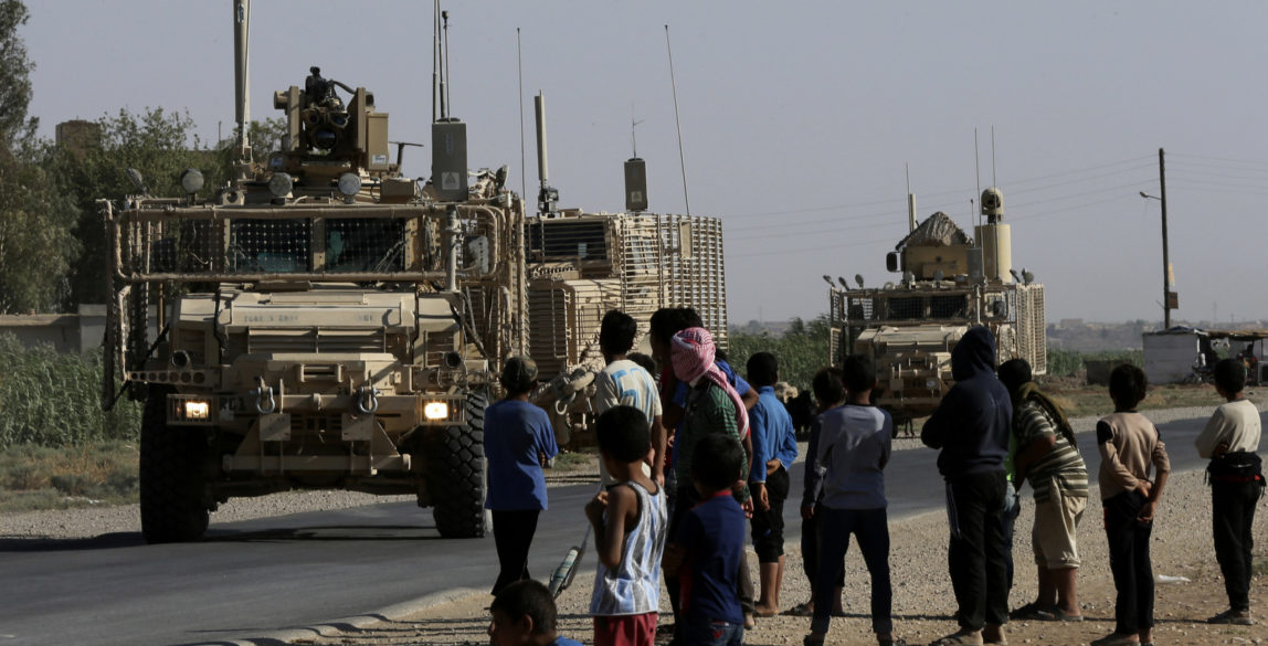 Syrian children watch a U.S. armored convoy pass on a road in northeast Syria, July 26, 2017. (AP/Hussein Malla)