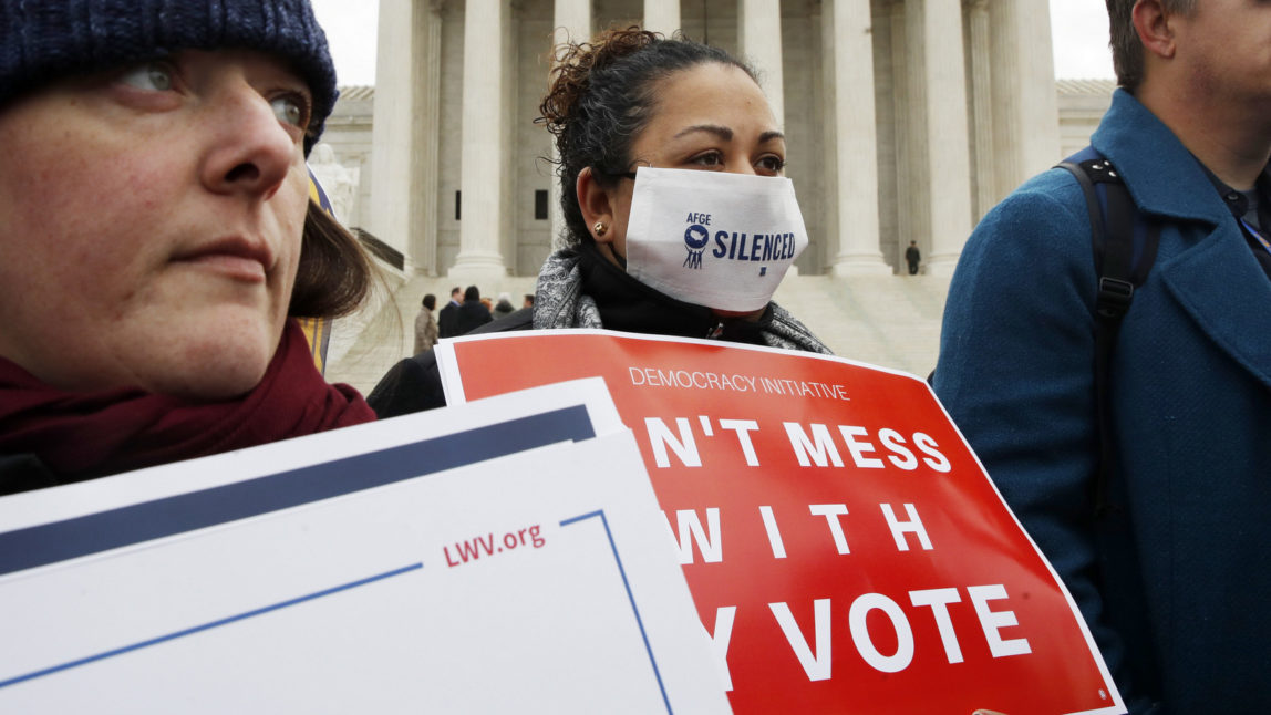 VoShannon Faulk, center, of San Antonio, Texas, wears a mask that says "silenced" while protesting with others outside of the Supreme Court in opposition to Ohio's voter roll purges, Wednesday, Jan. 10, 2018, in Washington. (AP Photo/Jacquelyn Martin)ter roll purges protest