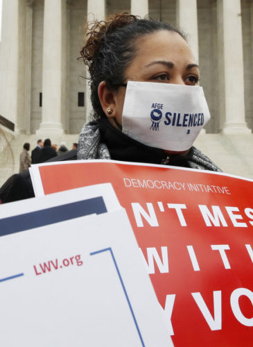 VoShannon Faulk, center, of San Antonio, Texas, wears a mask that says "silenced" while protesting with others outside of the Supreme Court in opposition to Ohio's voter roll purges, Wednesday, Jan. 10, 2018, in Washington. (AP Photo/Jacquelyn Martin)ter roll purges protest