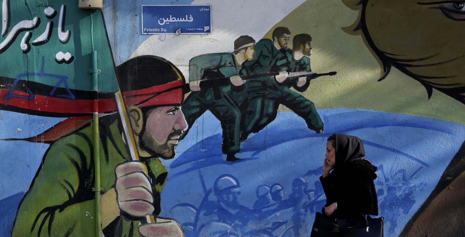 An Iranian woman walks past a mural depicting Iranian armed forces in the battlefield, at Palestine Sq. in Tehran, Iran, Jan. 16, 2016. (AP/Vahid Salemi)