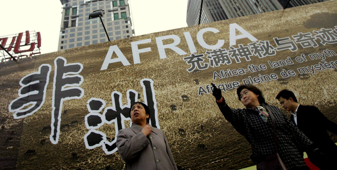 Chinese women stand in front of a billboard which promotes the China-Africa summit meeting, outside a hotel in Beijing. (AP/Greg Baker)