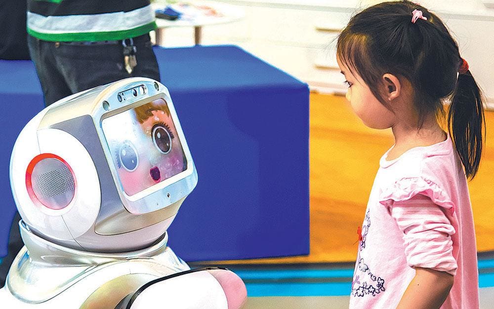 An AI powered robot interacts with a child at a tech and innovation expo in Nanjing, China. (China Daily)